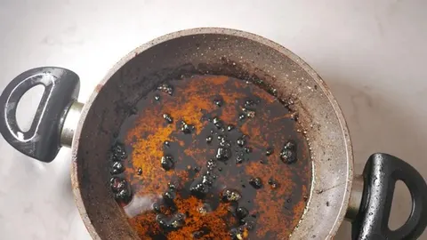Kuhinjska tava s tamnim, zagorjelim ostacima hrane i masnoćom