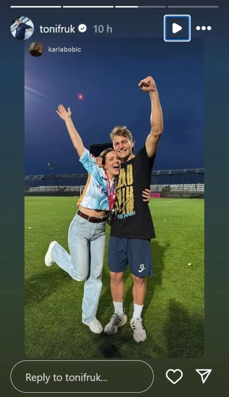 Par slavi na nogometnom terenu s podignutim rukama