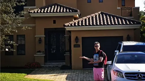 Muškarac u sunčanim naočalama stoji ispred moderne kuće s garažom