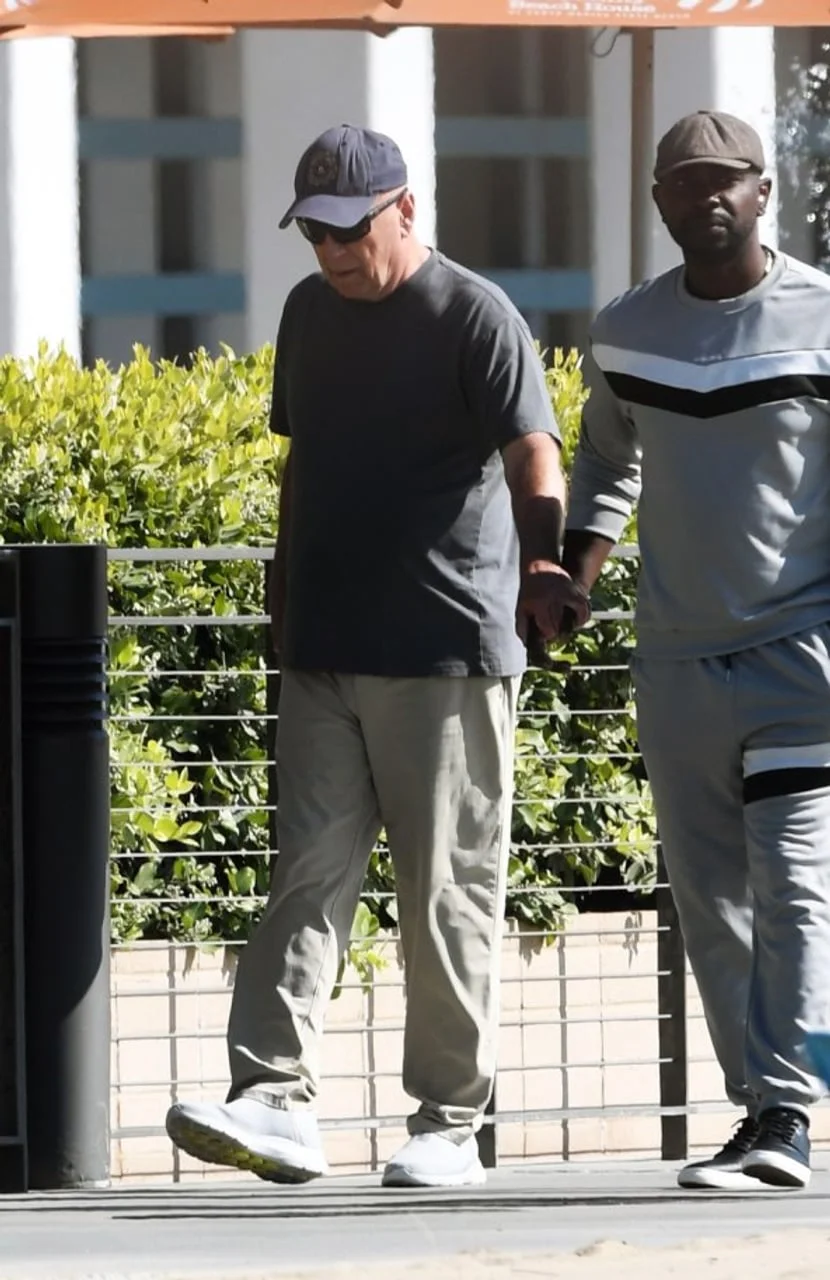 Bruce Willis u kapici i s naočalama drži ruku pratilca