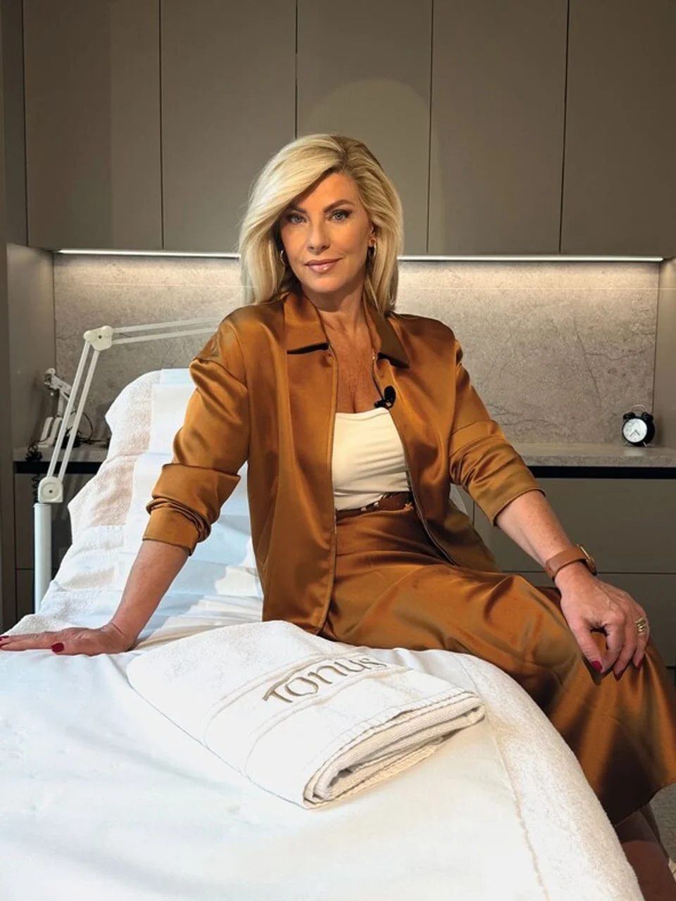 Žena u zlatnom odelu sedi na tretman stolu