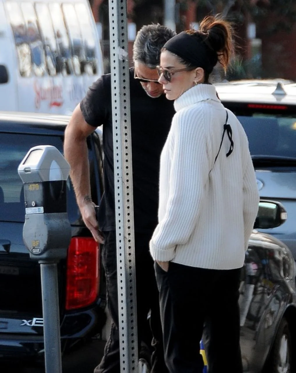 Sandra Bullock u bijelom džemperu stoji uz partnera pored auta