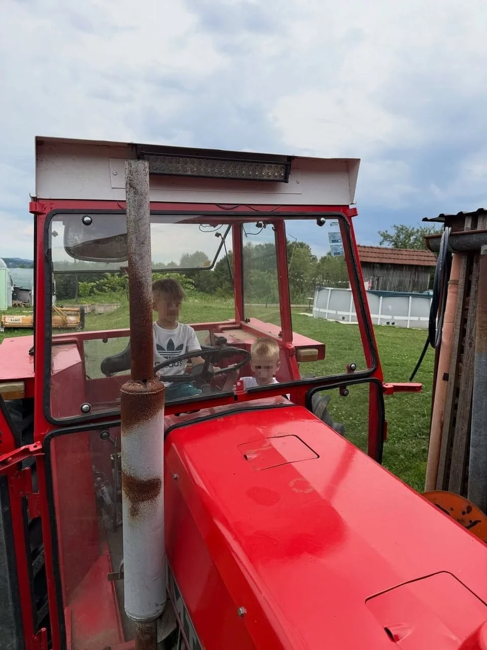 Dvoje male djece u kabini crvenog traktora