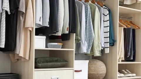 Redovi odjeće različitih boja poslagani u drvenom ormaru