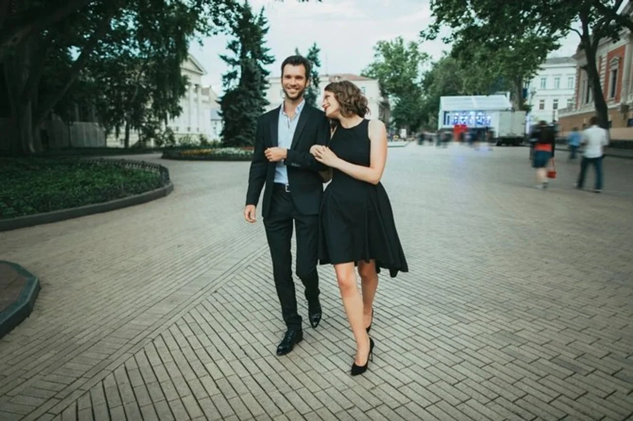 Par u elegantnoj crnoj odjeći šeta gradskom ulicom