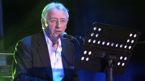 Oliver Dragojević pjeva u mikrofon s glazbenim notama ispred sebe