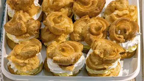 Zlatno smeđe princes krofne punjene bijelom kremom u bijelom posudu
