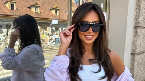 Žena s dugom, gustom smeđom kosom i sunčnim naočalama