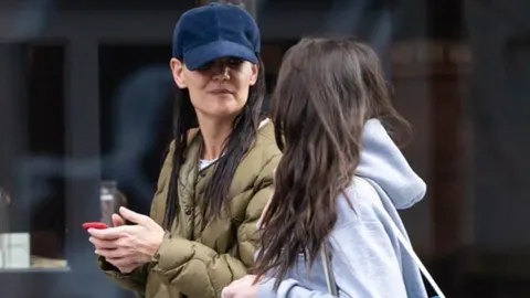 Katie Holmes u plavom kapu i zelenoj jakni razgovara s kćeri