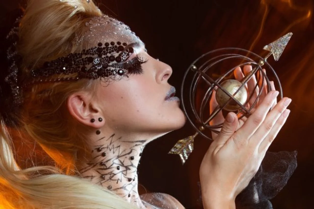 Profil žene s ukrasima na licu koja drži astrološki instrument