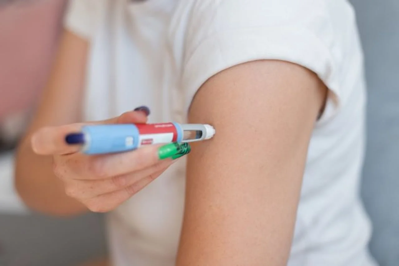 Ruka koja drži medicinski injektor pored nadlaktice