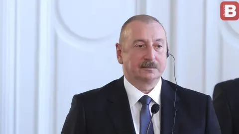 Portret muškarca u tamnom odijelu i plavoj kravati s mikrofonom