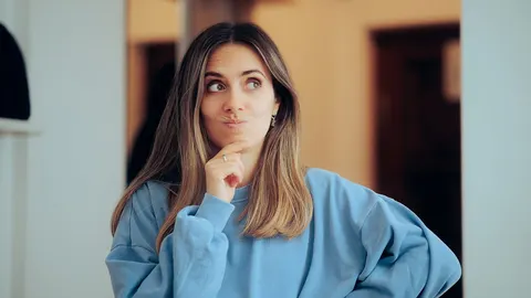 Žena u plavom dresu stoji u prolazu i zbunjeno razmišlja