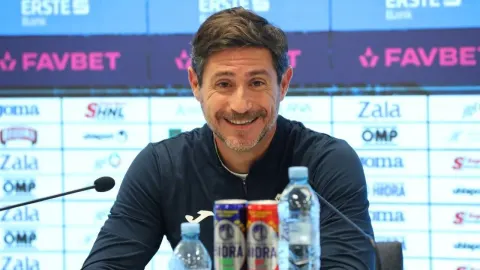 Trener Victor Sánchez sjedi za stolom na konferenciji za medije ispred sponzorskog zida.