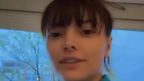 Ella Dvornik gleda u kameru dok se u pozadini vidi prozor i drveće