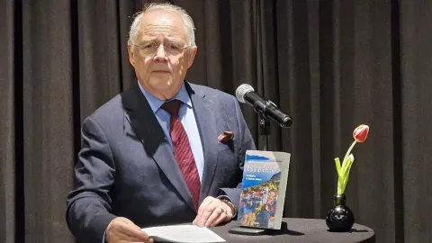 Manfred Matzka stoji za govornicom s knjigom o Istri i mikrofonom.