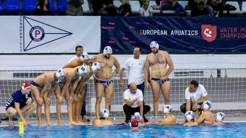 Vaterpolo momčad Primorca okupljena na rubu bazena sluša upute trenera.