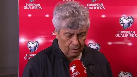 Mircea Lucescu daje izjavu ispred logotipa europskih kvalifikacija.