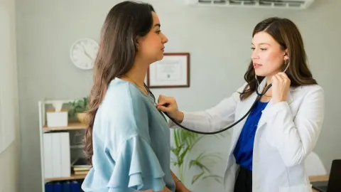 Liječnica u bijeloj kuti koristi stetoskop za pregled pacijentice u ordinaciji.