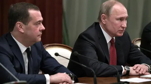 Vladimir Putin i Dmitrij Medvedev sjede za konferencijskim stolom ozbiljnih lica.