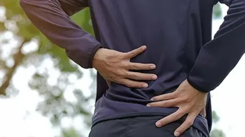 Muškarac se drži za donji dio leđa zbog bolova na otvorenom