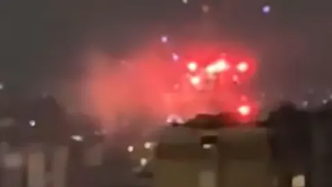 Crveni vatromet i bljeskovi na noćnom nebu iznad zgrada u Prištini.