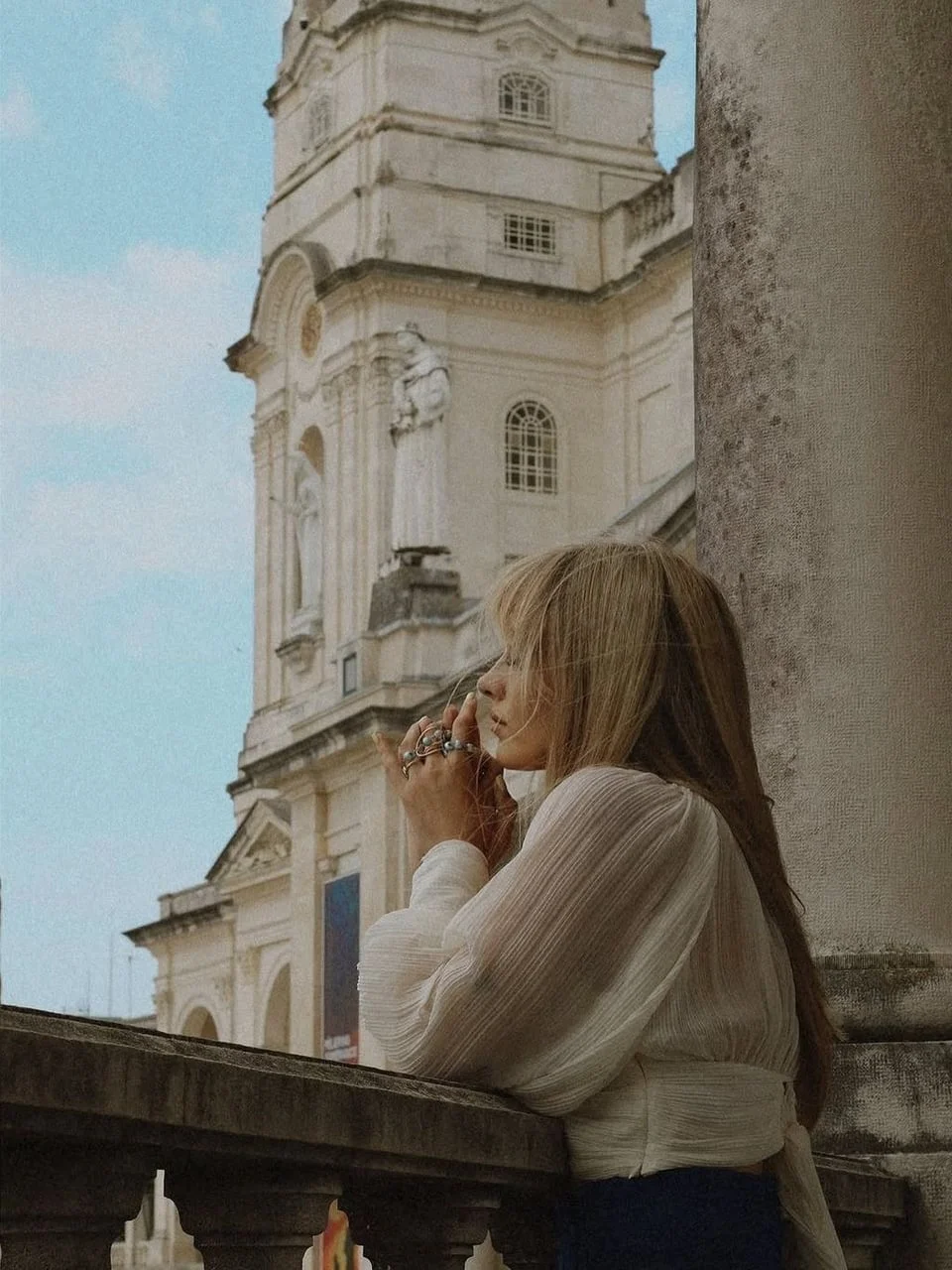 Djevojka okrenuta profilom moli ispred crkve