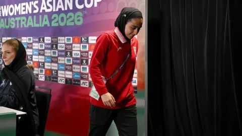 Iranska nogometašica s hidžabom hoda ispred panoa Azijskog kupa.