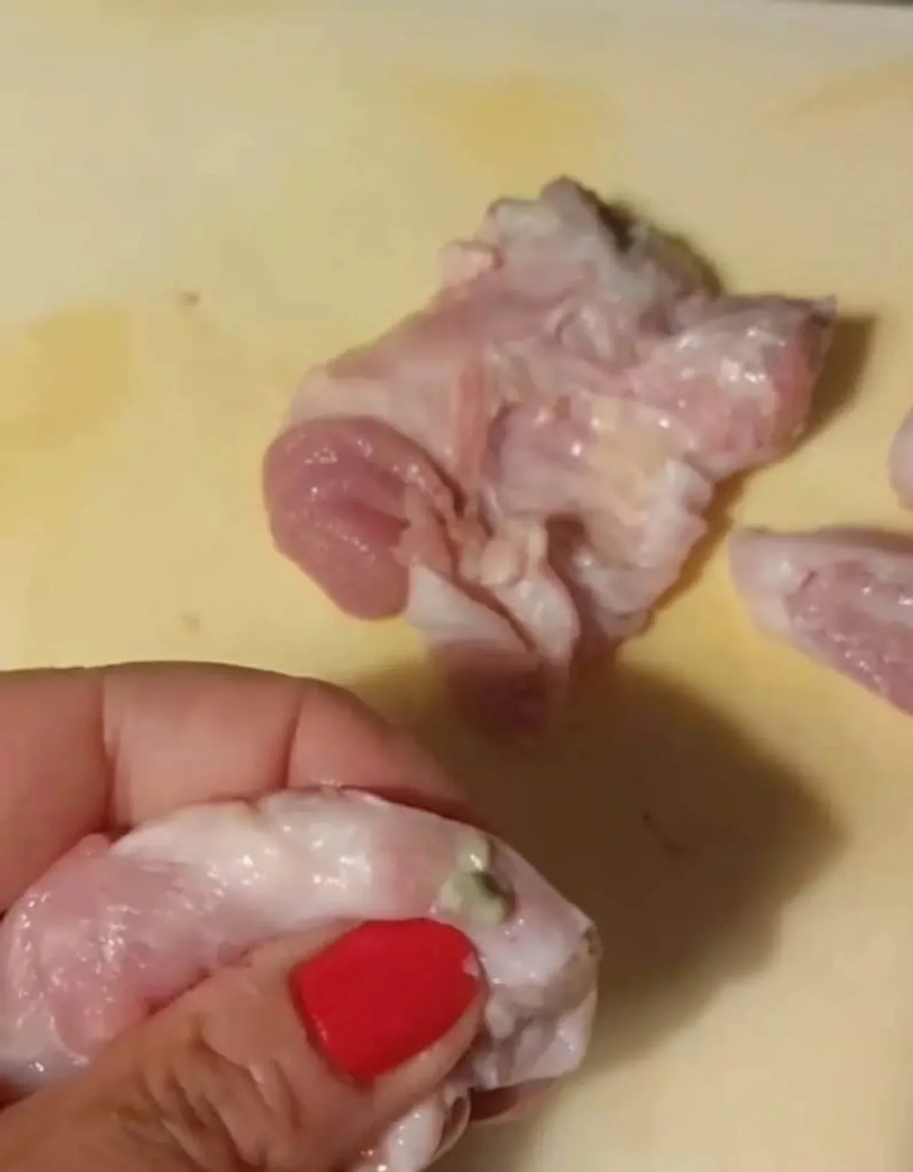 Ruka s crvenim lakom drži komad sirovine sa sumnjivom mrljom