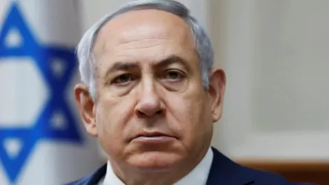 Krupni kadar Benjamina Netanyahua ispred izraelske zastave.