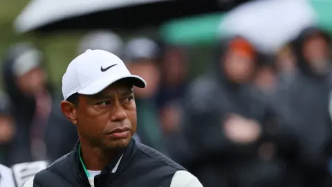Tiger Woods s bijelom kapom gleda u stranu s ozbiljnim izrazom lica na golf terenu.