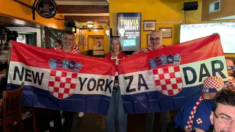 Hrvatski navijači u dresovima drže veliku zastavu s natpisom New York Zadar.