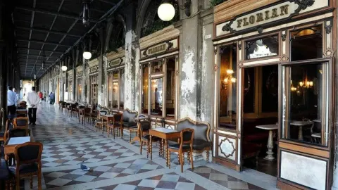 Povijesno pročelje i vanjski stolovi kafića Florian u Veneciji pod arkadama.