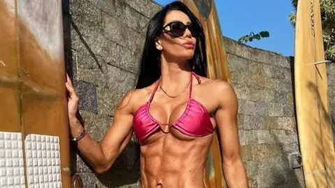 Michele Umezu u ružičastom bikiniju pozira pored dasaka za surfanje