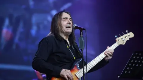 Dado Topić pjeva i svira bas gitaru na koncertnoj pozornici