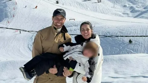 Rafael Nadal drži sina u naručju dok supruga Marija stoji pored njih na snijegu.