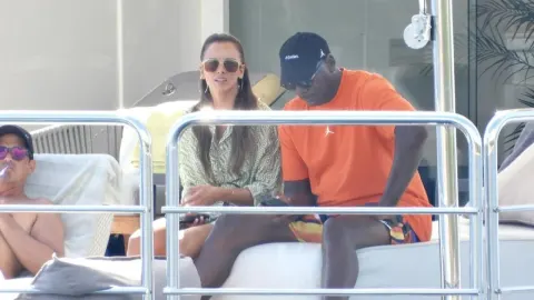 Michael Jordan u narančastoj majici sjedi na jahti sa suprugom Yvette Prieto.