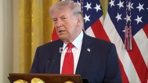 Donald Trump govori za govornicom ispred američkih zastava u Bijeloj kući.