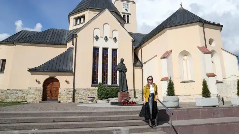 Žena stoji ispred crkve i kipa blaženog Alojzija Stepinca