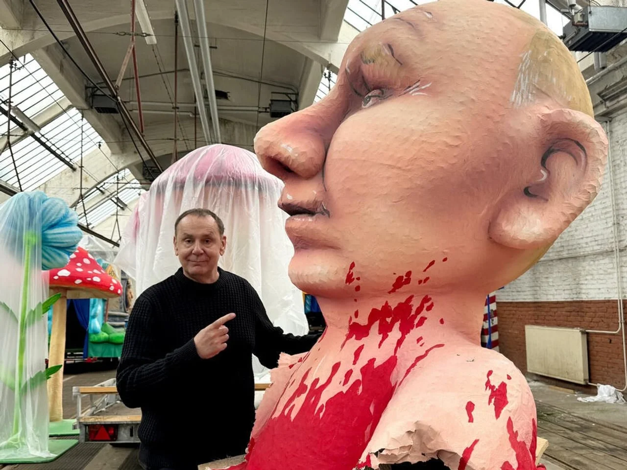 Umjetnik Žak Tili stoji pored velike biste s crvenom bojom koja simbolizira krv