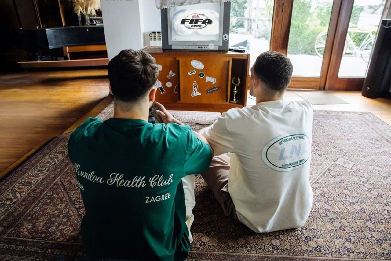 Pogled s leđa na Kovačića i Gvardiola dok igraju klasiku FIFA 2002 na starom TV-u.