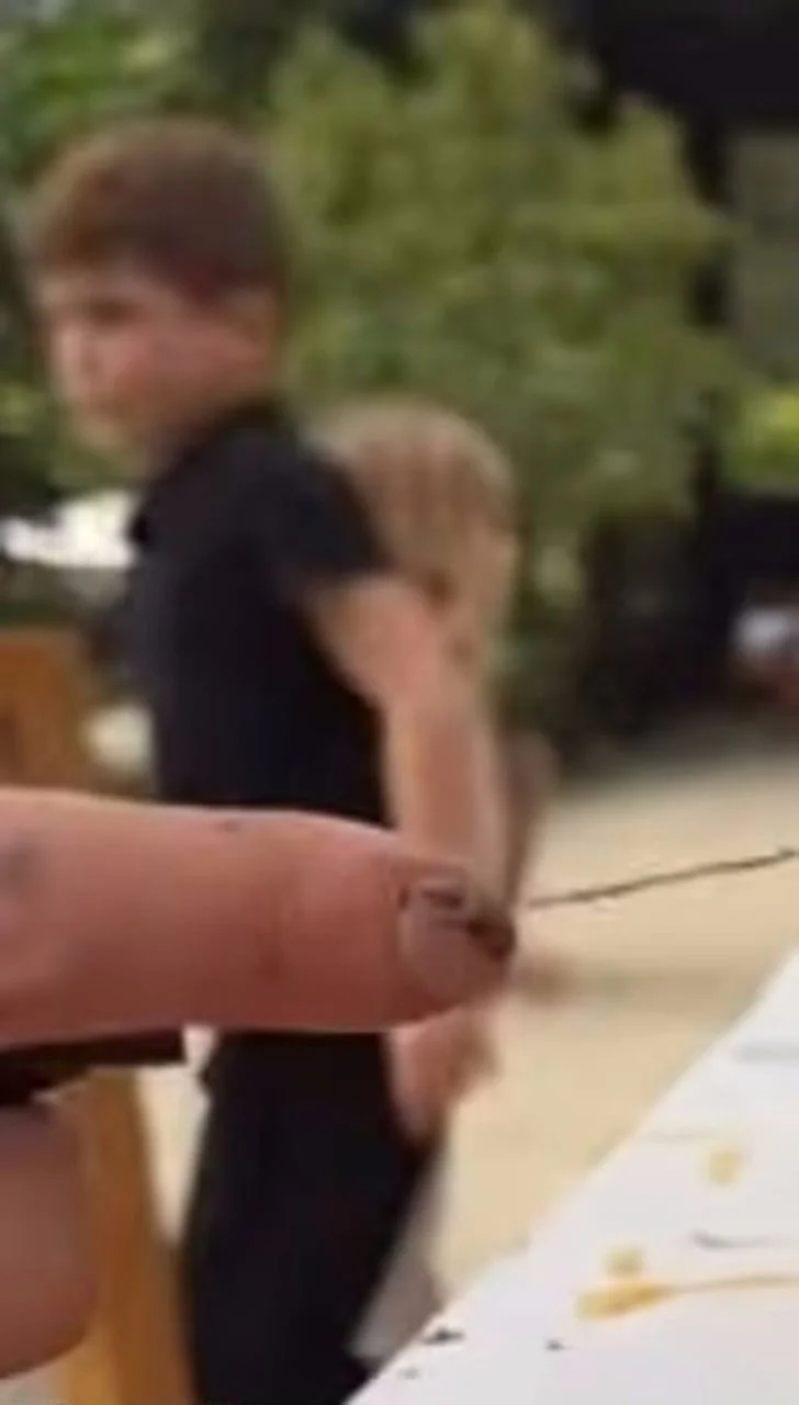 Mutna fotografija malog dječaka u crnoj majici na otvorenom prostoru.