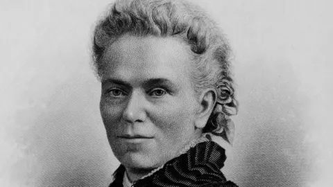 Crno-bijeli portret Matilde Joslyn Gage iz 19. stoljeća s cvijetom u kosi.