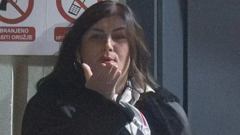 Gabrijela Žalac šalje poljubac rukom ispred ulaza sa znakovima zabrane.