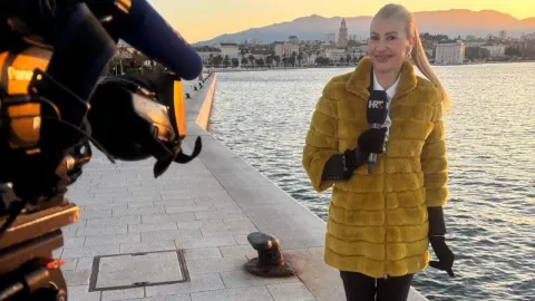 Regina Zubanović s mikrofonom u ruci izvještava ispred splitske rive i mora.