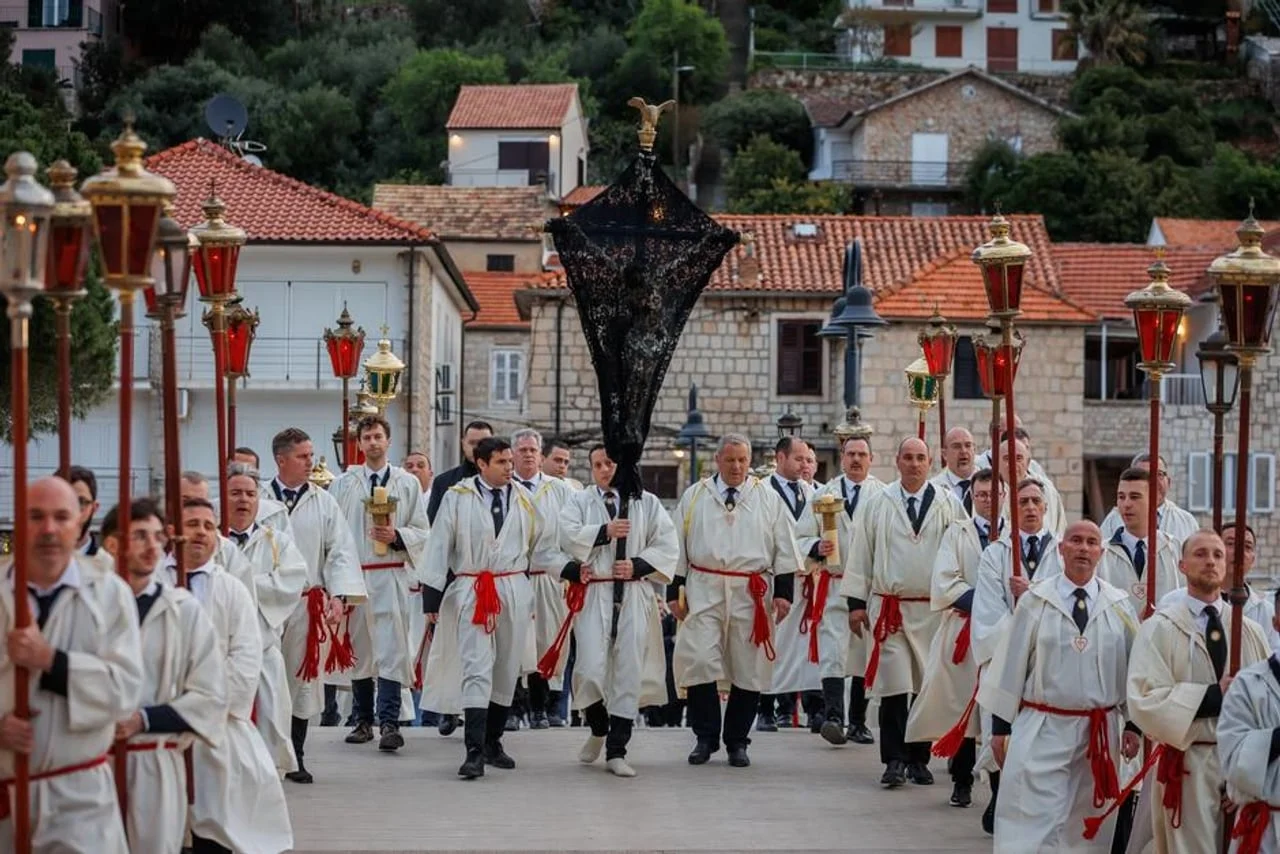 Procesija muškaraca u bijelim tunikama nosi raspelo