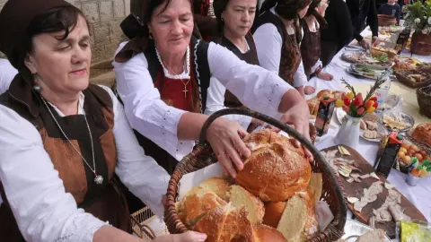 Žene u narodnim nošnjama drže košaru s blagoslovljenim kruhom