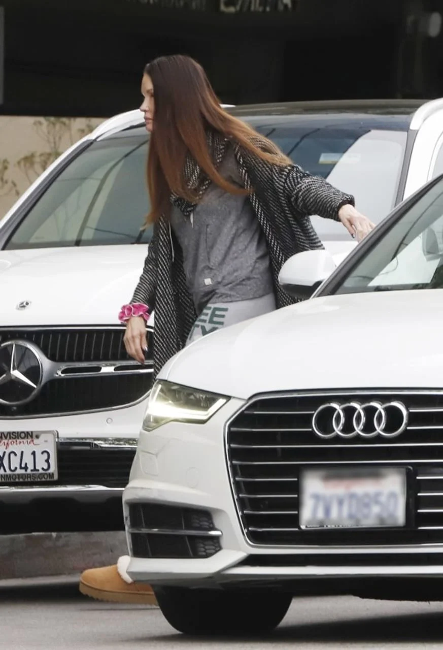 Janice Dickinson izlazi iz bijelog automobila na parkiralištu.