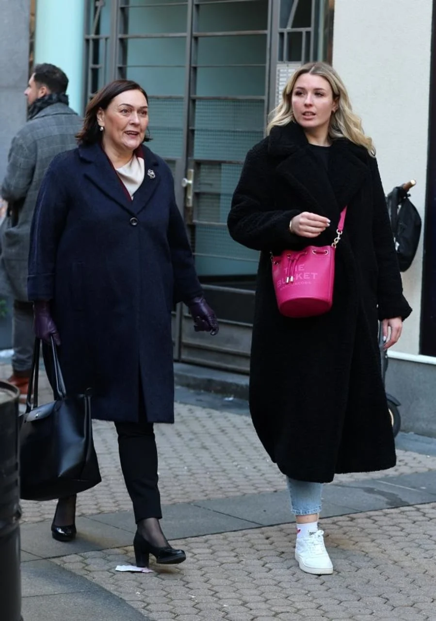 Dvije žene u tamnim kaputima hodaju gradskom ulicom.