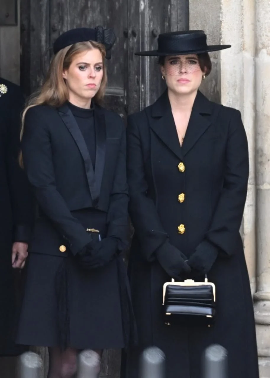 Portret princeza Beatrice i Eugenie u crnim kaputima ispred ulaza